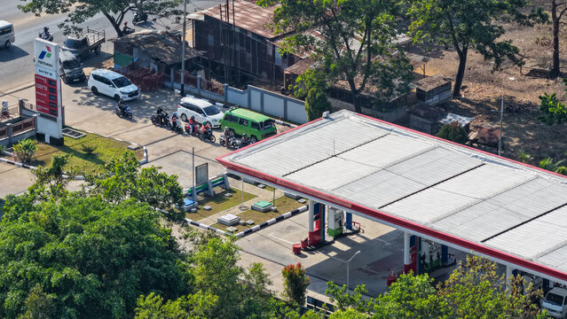 Cars and motorcycles line up to get fuel at a Pertamina station during a bright morning in Borneo