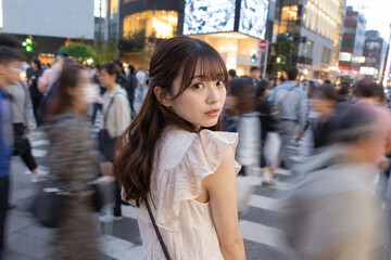Fototapeta premium 人通りのある街で白いフリルブラウスを着る女性