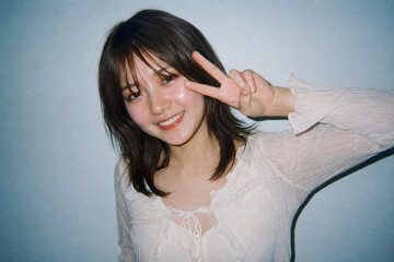 Fototapeta premium 白いブラウスでピースサインをする女性