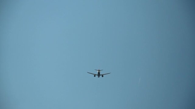 Commercial passenger airplane captured from below against a clear blue sky. Minimal aviation background with copy space