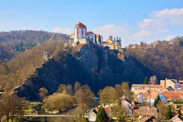 Majestic baroque castle on rocky hill overlooking quaint village in spring landscape © Iurii Gagarin