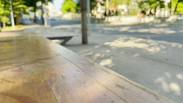 An empty wooden bench waits quietly at a sunny bus stop in Simferopol, Crimea. This lonely scene brings a peaceful and nostalgic feeling.