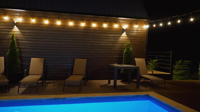 Luxurious private swimming pool glowing with vibrant blue lights in a tranquil backyard setting at night, with warm string lights creating a cozy and inviting atmosphere for relaxation or a party