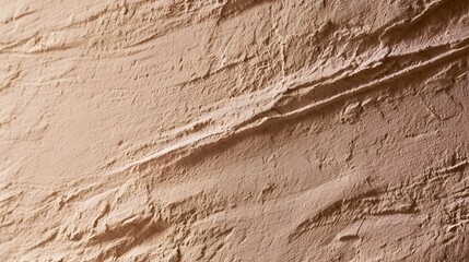 Fototapeta premium Close up of textured beige plaster wall surface showing layered brush strokes and natural material grain