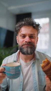 A man enjoying a fresh croissant and coffee for breakfast