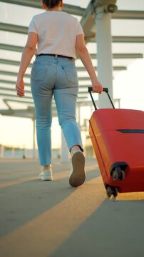 Woman confidently pulling a suitcase in an airport terminal. Back view