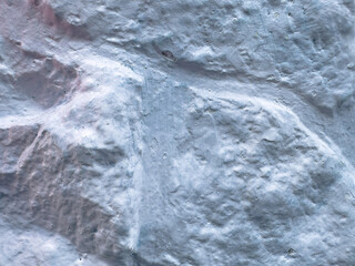 Obraz premium Detailed close-up of a rough white painted stone wall with raised masonry, uneven coating and naturally weathered surface.