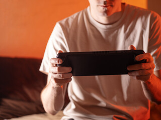 man holds a portable game console, playing video games © pavelkant