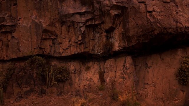 Drone Horizontal Backward Flight Approaching an Overhanging Massive Red Rock Cliff, Dusk, Chile