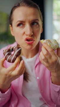 Woman with eating disorder eating two donuts with pleasure and at the same time