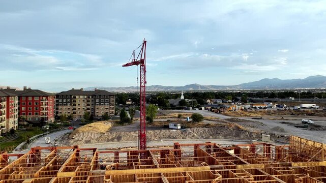 Wood-frame apartment construction with tower crane, framed structures, active earthworks and surrounding residential neighborhoods in Taylorsville, Salt Lake County, Utah, Salt Lake Valley, USA.