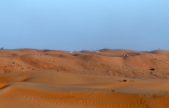 View of off-road vehicles driving across the vast orange sand dunes of the Wahiba Sands desert in Bidiyah, Ash Sharqiyah North G, Oman.