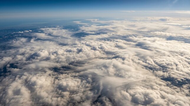 Aerial view of sweeping white clouds over mountain landscape beneath clear blue sky, majestic flight perspective and peaceful atmospheric scenery.