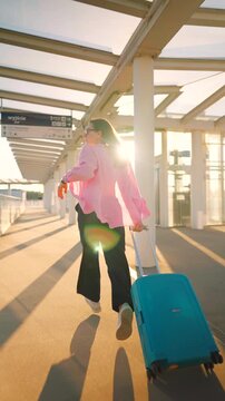 Caucasian woman pulling a suitcase and running, late for flight. 