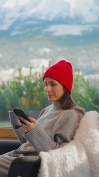 A woman using smartphone and drinking coffee in a quiet cabin.