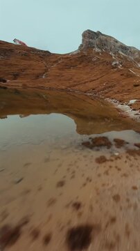 FPV drone flying along the surface of mountain cliffs of Cristallo mountain.