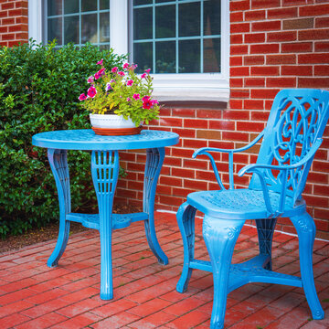 Blue metal bench and table with vase of flowers in the front yard