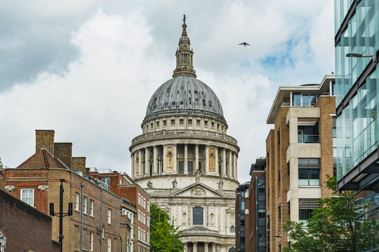 View of the iconic dome of St. Paul's Cathedral framed by historic brick buildings and modern glass architecture in London, England, United Kingdom.