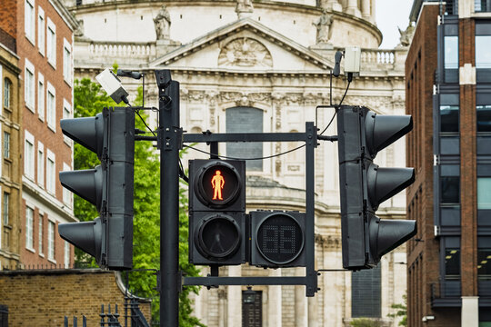 View of a traffic light displaying a red pedestrian signal with the historic St. Paul's Cathedral in the background in London, England, United Kingdom.