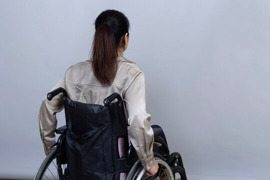 Woman using a manual wheelchair, viewed from behind, demonstrating independent mobility, accessibility, disability inclusion, adaptive living, and freedom of movement.