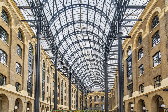 View of the elegant glass-roofed atrium with arched brick walls and black steel pillars in a historic London arcade, London, England, United Kingdom.