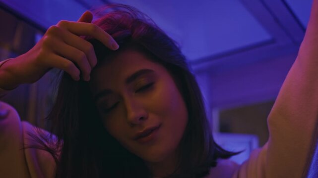 Brunette touching hair neon light close up. Sensual female portrait night party.