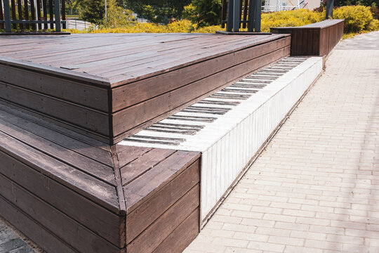 Wooden outdoor stage platform with step painted like piano keys in city park for creative urban architecture music design and public space installation concept