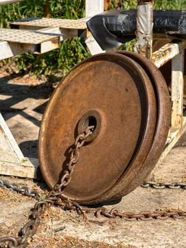 Old chained iron weight plates on an outdoor sports ground with weathered homemade exercise equipment for resistance training and fitness workouts