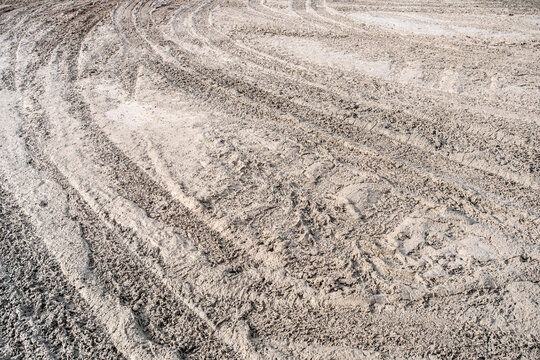 Rough ground soil texture background with wheel tracks