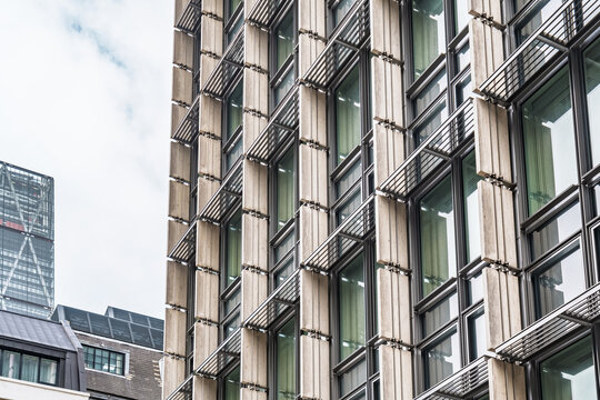 View of the modern glass facade of a building featuring vertical stone fins and metal sunshades in London, England, United Kingdom.