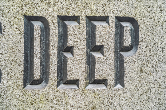 View of the word DEEP carved into a textured stone surface in London, England, United Kingdom.