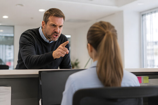 Angry customer pointing at a stressed office employee during a heated verbal confrontation, capturing workplace harassment, customer aggression and professional conflict.