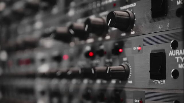 Sound Engineer Adjusting Audio Hardware Controls and Power Switch in Professional Recording Studio