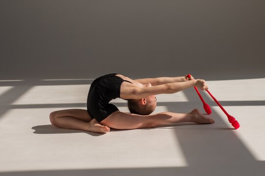 Little gymnast posing with clubs on white background. 