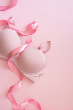Breast cancer awareness month concept with pink bra and ribbon on soft vertical pink background showing support