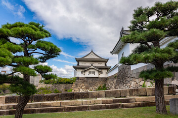 Obraz premium Famous Osaka Castle tower rising above green landscape and traditional Japanese fortress architecture, Osaka, Japan