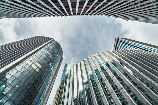 View of modern glass skyscrapers reaching towards a cloudy sky in the financial district of London, England, United Kingdom.