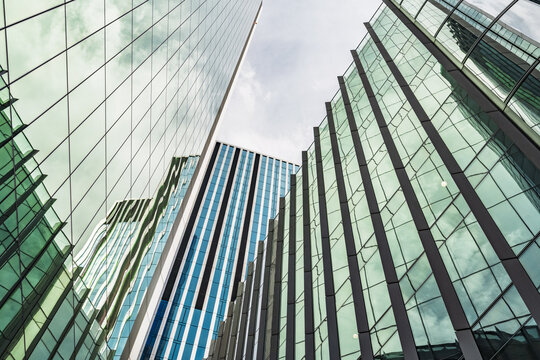 View of modern glass skyscrapers with reflective facades reaching towards the sky in the financial district of London, England, United Kingdom.