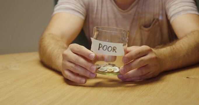 Person showing an almost empty jar labeled &ldquo;Poor,&rdquo; representing insufficient money, poverty, financial hardship and cost-of-living struggles.