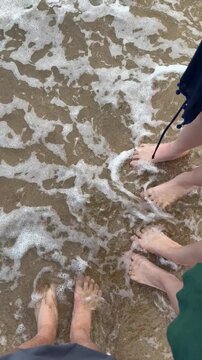 Feet of father, mother, and daughter on the beach, point of view