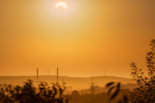 12 August 2026, a partial solar eclipse appears over Altbach power plant chimneys and Stuttgart TV tower, seen from Rossw&auml;lden, Germany.