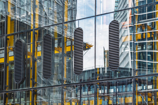 View of the Lloyd's building facade with its yellow steel structural elements, glass panels, and ventilation grilles London, England, United Kingdom.