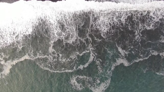 Aerial Drone Top Down View of Atlantic Ocean Waves Crashing on Black Volcanic Sand Beach Iceland