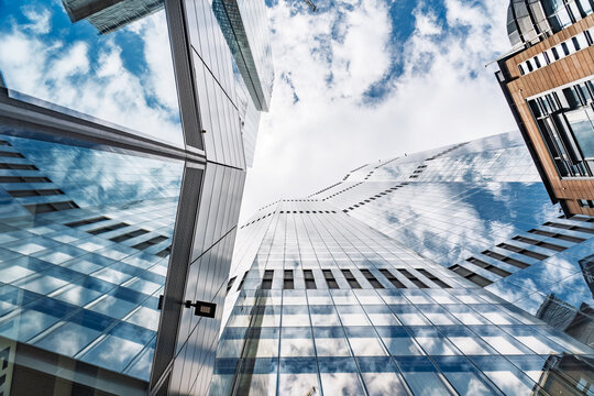 View of modern glass skyscrapers reflecting the blue sky and clouds in the financial district of London, England, United Kingdom.