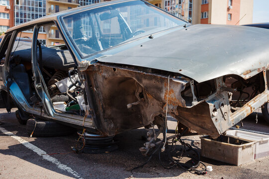 Rusty car body with corrosion, damaged chassis, metal decay, neglected maintenance and repair.