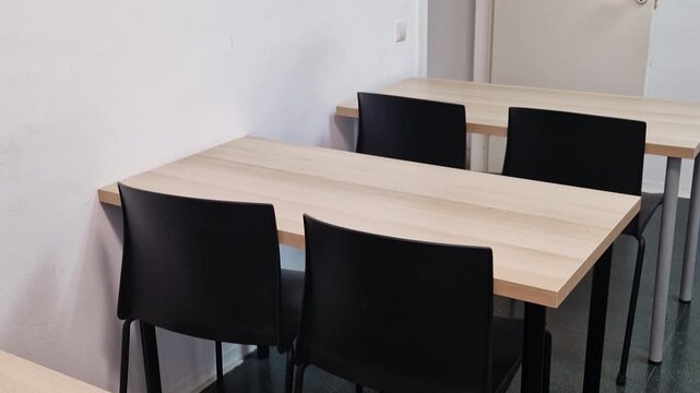 Empty desks and black chairs inside a bright classroom at a language school