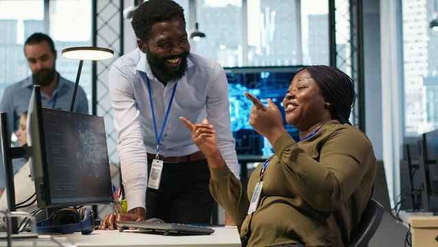 Cheerful programmers chat in the office while using AI to automate repetitive tasks and speed up software feature implementation together.