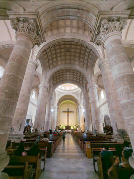 View of the interior of the Cathedral of San Ildefonso with stone columns, vaulted ceilings, and wooden pews in Merida, Yucatan, Mexico.