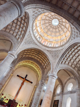 View of the interior of the Catedral de Merida featuring a large coffered dome, stone columns, and a crucifix on the wall in Merida, Yucatan, Mexico.