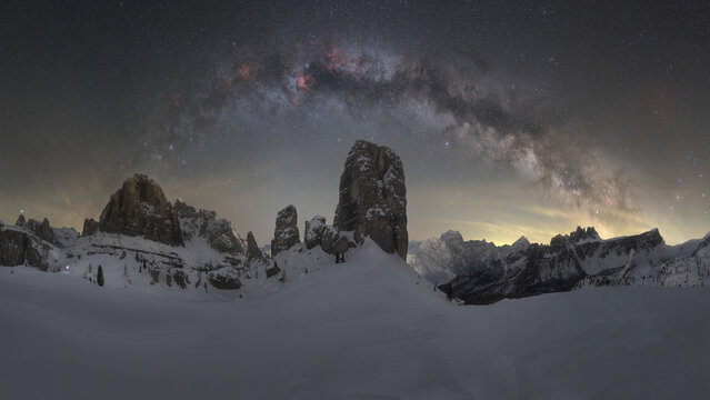 View of Cinque Torri rock formations covered in snow under a starry night sky with the Milky Way galaxy visible above the Dolomites in Cortina d'Ampezzo, Veneto, Italy.